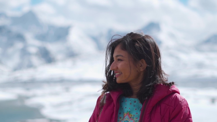 Portrait of tourist Indian girl looking at snow covered mountains at Shinku La Pass, Himachal Pradesh, India. Travel lifestyle. Female travel influencer enjoying vacation in mountains | Shutterstock HD Video #1097368221