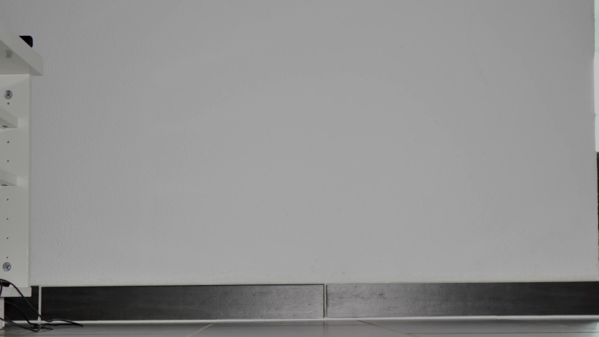 A woman in shiny black leggings walks through her living room, then she stops and nervously taps her red Stilletos on the floor, after which she stomps energetically on the floor