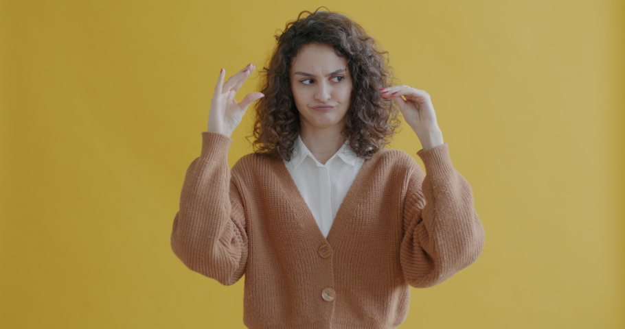 Portrait of cute young woman tired of blabbing showing bla bla bla hand gesture and looking at camera on yellow background. People and expression concept. | Shutterstock HD Video #1097372863