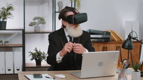 Senior businessman programmer software developer using headset helmet app to play simulation game. Watching virtual reality 3D 360 video. Senior old grandfather in VR goggles working at home office
