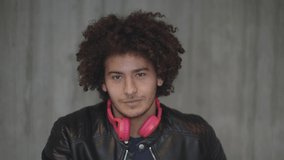 close-up portrait of a cheerful smiling north african man with curly hair and headphone looking at camera