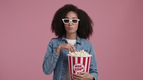 Cute girl with ethnic hair wearing 3d glasses while watching a movie. Portrait of a stylish, young woman enjoying tasty popcorn. High quality 4k footage