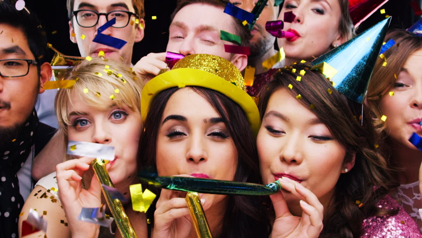 Party blower, confetti and group of people enjoying time together. Holiday event, celebration and happy friends blowing birthday whistle, having fun with hats and partying on dark studio background. Royalty-Free Stock Footage #1097378825