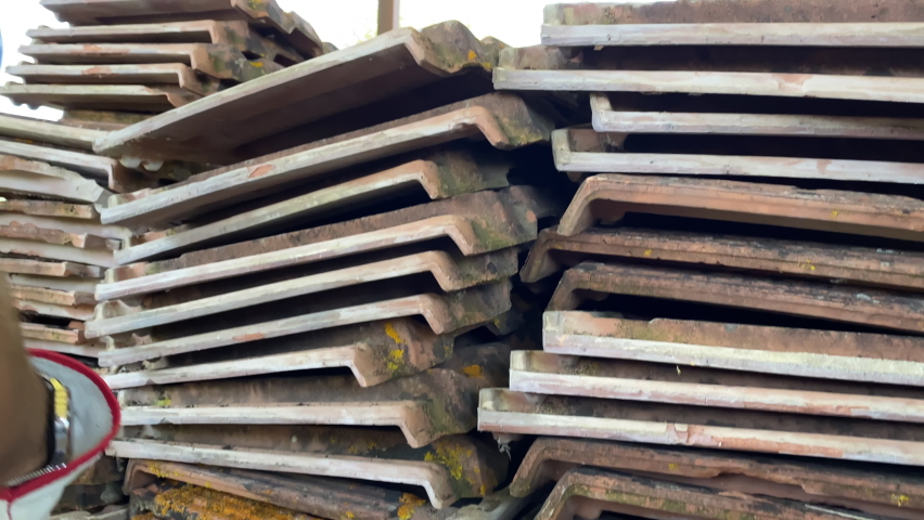 Stack of demolished red clay roof tiles outdoor, weathered ceramic shingle unusable for covering house roof, construction site garbage ready for recycle. Dismantling ruined terracotta roof tiles - Powered by Shutterstock - Get 15% off with code: PIKWIZARD15