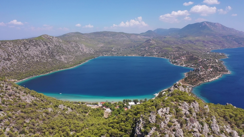 Aerial drone video of scenic lake Vouliagmeni in Corinthia near famous lighthouse of Heraion and city of Loutraki featuring crystal clear turquoise beach and calm waters, Perachora, Greece