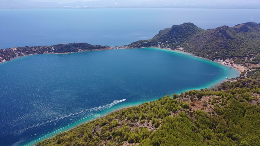 Aerial drone video of scenic lake Vouliagmeni in Corinthia near famous lighthouse of Heraion and city of Loutraki featuring crystal clear turquoise beach and calm waters, Perachora, Greece