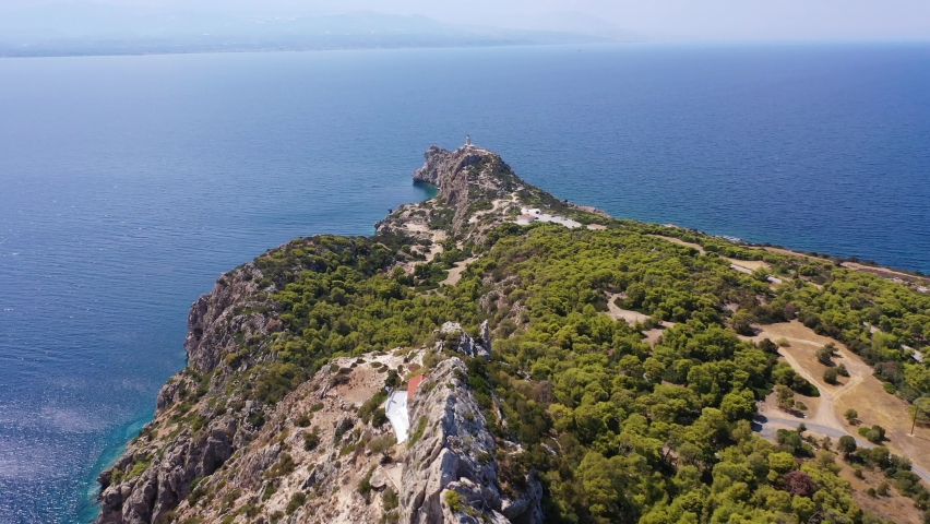 Aerial drone video of famous archaeological site of Heraion in Cape Melagavi featuring a small beach next to iconic lake Vouliagmeni and lighthouse, Corinthian bay, Perachora, Loutraki, Greece