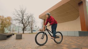 stunt bicycling in park, young boy is riding bmx bike, doing tricks, rotating wheel and handlebar - Powered by Shutterstock - Get 15% off with code: PIKWIZARD15
