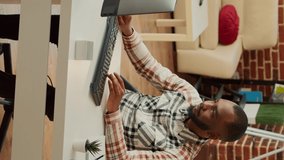 Vertical video: African american man working on computer at desk, doing remote task at home with girlfriend. Young adult using online web app to plan financial data for company report, send email.