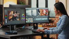 Asian filmmaker editing video and audio footage on multi monitors, creaating movie with professional studio montage. Female videographer using color grading to edit clips in post production agency.