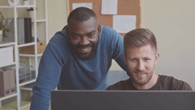 Two diverse male programmers working together in modern IT office discussing software development on desktop computer - Powered by Shutterstock - Get 15% off with code: PIKWIZARD15