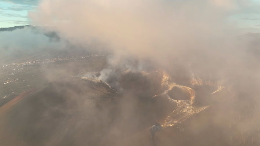 Aerial view of Volcano at Cumbre Vieja, La Palma at sunset with white and black smoke plumes and ashes in the Canary Islands