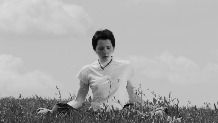 A woman sitting on the grass and doing exercise with dumbbells. Black and white. Nature landscape.