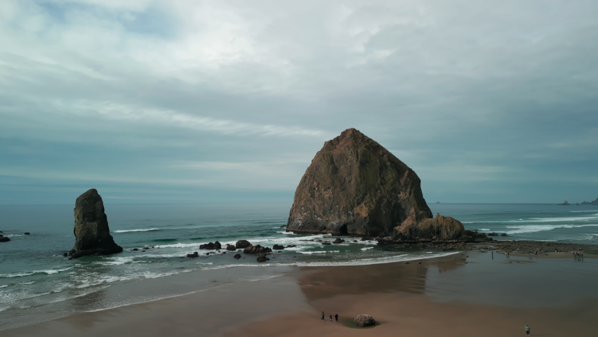 Wide Aerial shot of Haystack Rock beach in coastal town Cannon Beach, Oregon. Wide drone shot 