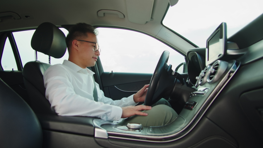 Young asian businessman driver in car, sharing concept, vehicle and transport. Korean happy guy driving, sitting in new luxury car and smiling. Traveling by automobile. | Shutterstock HD Video #1097401007
