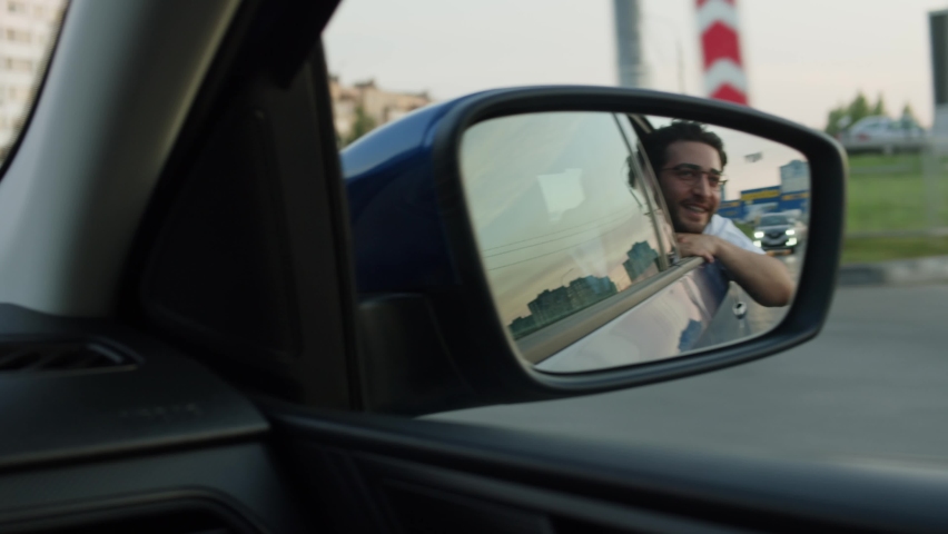 Young Man Looking in Wing Mirror in Car close-up. Car Sharing concept, Vehicle and Transport. Spanish Happy Guy Driving, Smiling Passenger in Taxi. Traveling by Automobile. | Shutterstock HD Video #1097401009