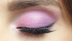 Closeup macro slow motion video of human female eye. Woman with vogue face beauty makeup. Girl with perfect skin and pink eyes shadows.