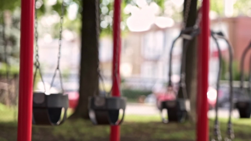 Empty swings slowly moving on the park playground. Summer sunny day. Green trees on the background. Lockdown. Quarantine and isolation | Shutterstock HD Video #1097408775