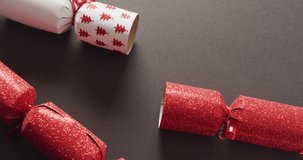 Animation of christmas greetings text over christmas crackers decorations. Christmas, festivity, celebration and tradition concept digitally generated video.