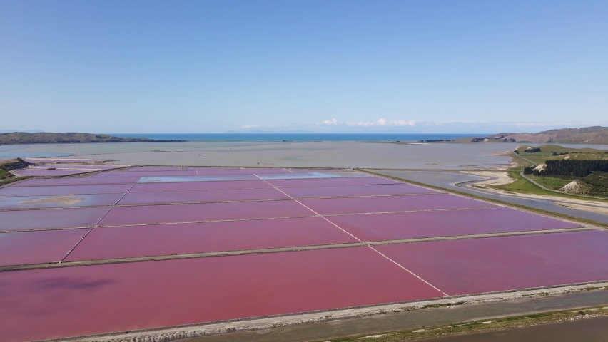 Vibrant pink Salt works ponds with Ocean view behind, Aerial dolly shot.