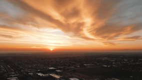4k Drone footage over a city in California with a dynamic sunrise with orange clouds and a pin drop sun. 