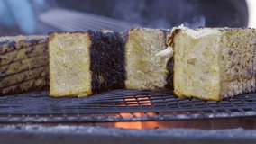 Close-up shot of juicy, organic food roasted on a grid with orange flames. Detailed view of open fire, outdoor kitchen with steel equipment. High quality 4k footage