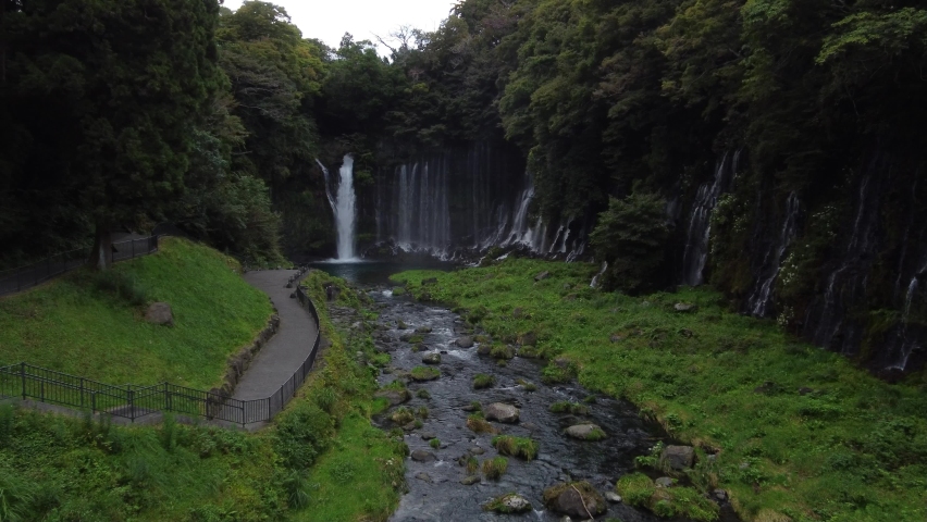 Lush greenery surrounds a waterfall in Japan. | Shutterstock HD Video #1097414495