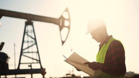 oil industry. engineer next to an oil rig signs a paper contract. oil production business finance concept. gas production. a sun worker oil production next an station. a worker in hard hat works - Powered by Shutterstock - Get 15% off with code: PIKWIZARD15
