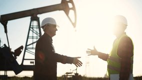 handshake business oil contract. handshake a worker and businessman shaking hands against the backdrop of an oil pump. oil extraction sun business concept. silhouette handshake business contract - Powered by Shutterstock - Get 15% off with code: PIKWIZARD15