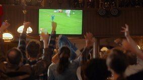 Group of Soccer Fans Watching a Live Football Match in a Sports Bar. People Standing in Front of a TV, Cheering for Their Team. Player Scores a Goal and Crowd Celebrate Winning the Championship. - Powered by Shutterstock - Get 15% off with code: PIKWIZARD15