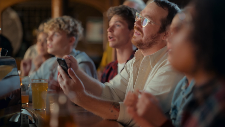 Portrait of a Happy Young Man Holding a Smartphone, Anxious About the Sports Bet on a Soccer Match. Looking at the Screen While Sitting at a Counter, Getting Very Emotional After Winning the Bet. | Shutterstock HD Video #1097419567