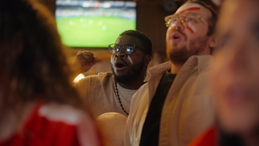 Close Up Portraits of a Diverse Group of Supportive Soccer Fans with Painted Faces Standing in a Bar, Cheering for Their Team. Raising Hands and Shouting. Friends Celebrate Victory After the Goal.