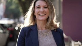 Happy mature woman walking outdoors. Mature middle age person walks outdoors in urban city street. Portrait of a joyful older lady - Powered by Shutterstock - Get 15% off with code: PIKWIZARD15