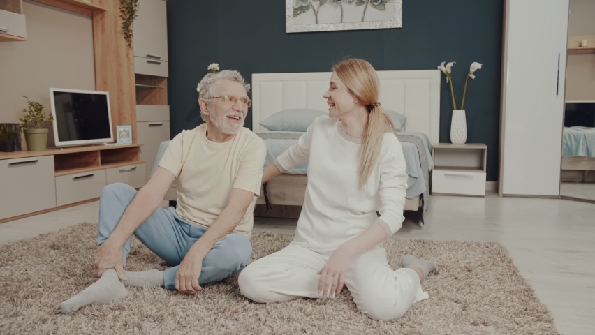 Dad and daughter are laughing and having a good time. An elderly man is doing yoga with his daughter. Happy family. sincere emotions. Morning gymnastics. Health care.