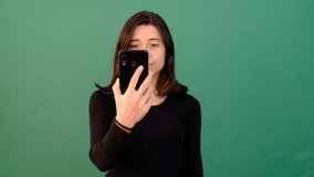 Woman showing green screen phone, smiling young girl pointing at telephone screen, smartphone with green screen isolated green background
