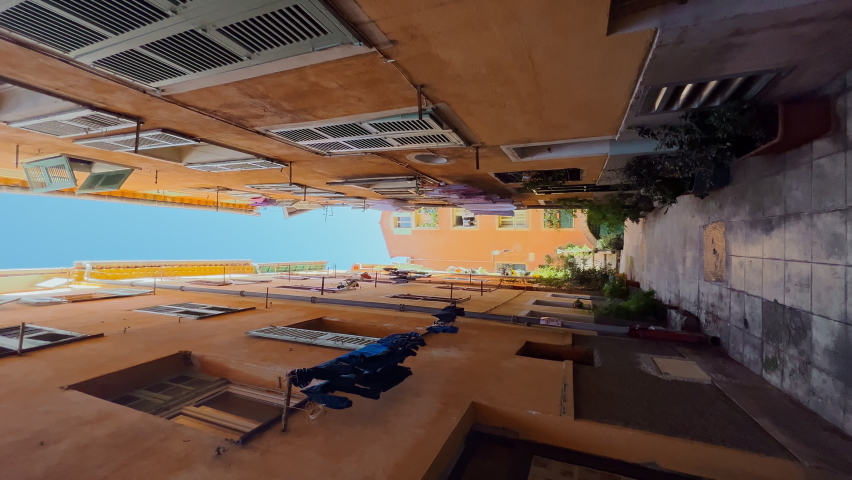 steps up among the narrow streets of the old city of Nice, France, laundry hanging drying on the facades of buildings, parked bicycles and bikes, lots of flowers on the windows, lanterns on the walls