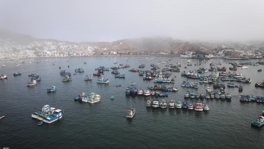Drone shot of fishing boats in a fishing port next to beach houses and yachts in the cost of Pucusana Peru during summer Royalty-Free Stock Footage #1097449647