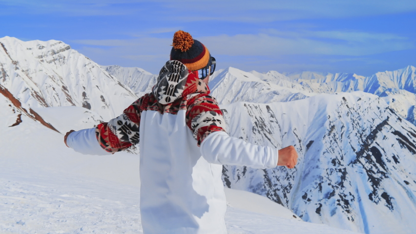 Man snowboarder on goggles stretching at blue sky background before go down snowy slope in Swiss or Austrian mountain. Having good time during Christmas holiday. Active lifestyle extreme sport concept