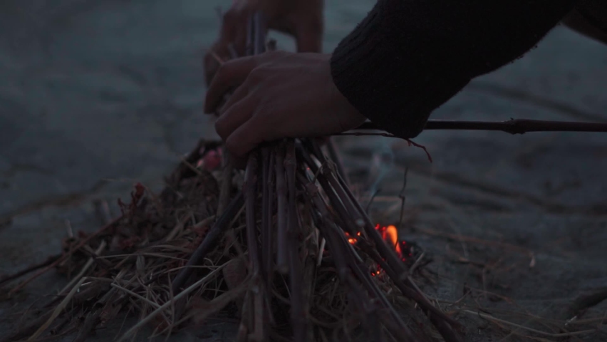 Closeup shot of hands of an Indian man fixing twigs to prepare bonfire after the sunset at Manali in Himachal Pradesh, India. Hiker making bonfire in the night to keep himself warm in the winter.  | Shutterstock HD Video #1097455767