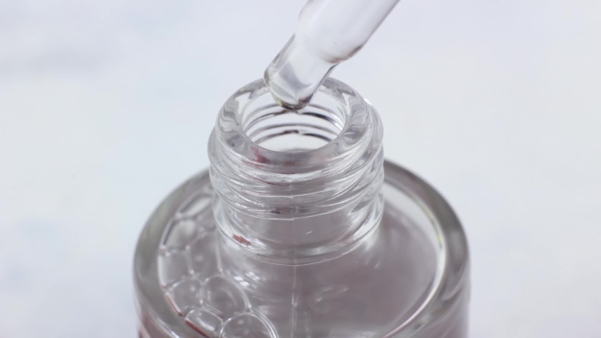 The pipette dropping a transparent liquid into dropper bottle on light background close up | Shutterstock HD Video #1097462609