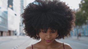 Cinematic video of a self confident young woman spending time in a modern city. Millennial girl with afro hairstyle lifestyle moments.	