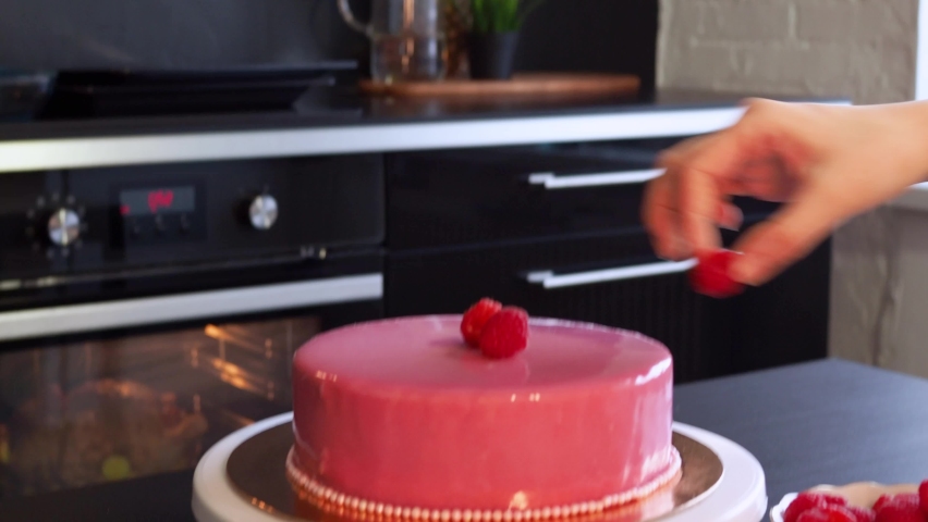 A woman in an apron bakes and decorates a cake at home. Beautiful pink cake with raspberries, sweet dessert. Home pastry chef | Shutterstock HD Video #1097464801