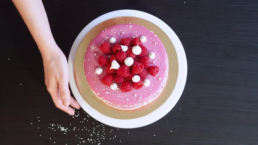 A woman in an apron bakes and decorates a cake at home. Beautiful pink cake with raspberries, sweet dessert. Home pastry chef | Shutterstock HD Video #1097464803
