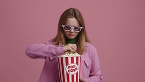 Portrait of a woman watching a drama movie in the cinema. Young girl holding a bucket of popcorn and wearing 3d glasses. High quality 4k footage