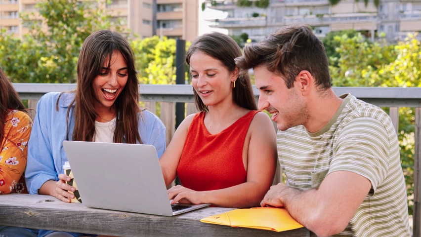 A group of three young students doing homeworks searching information on internet at university campus with laptop computer. Two happy ladies and one concentrated guy studing the lesson with a