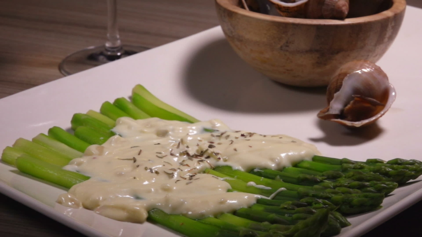 Cooked sea escargo snails with a side dish of boiled green asparagus under the cheese sauce | Shutterstock HD Video #1097467135