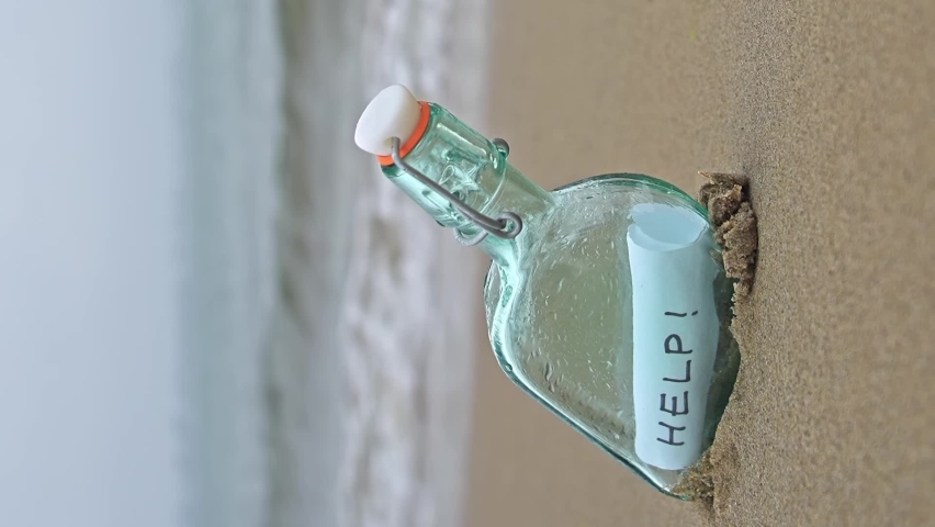 Bottle on beach with help message on paper inside vertical video