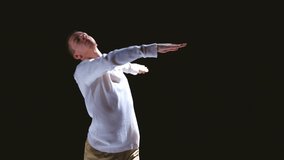 Solo performance of young man in white costume dancing contemp dance in darkness of studio at bright spotlight. Modrn art, action, dance, music, emotions, energy. Video, 4k