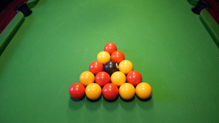 Pool balls racked in a triangle are struck by the white ball. The break spits the balls as the roll off across the pool table. | Shutterstock HD Video #1097475543