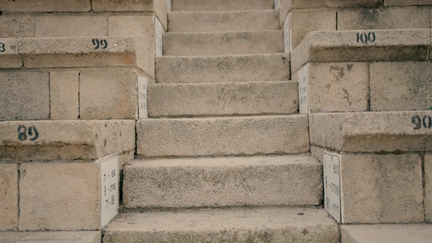 A woman in high heels descends the stairs in the ancient amphitheater.